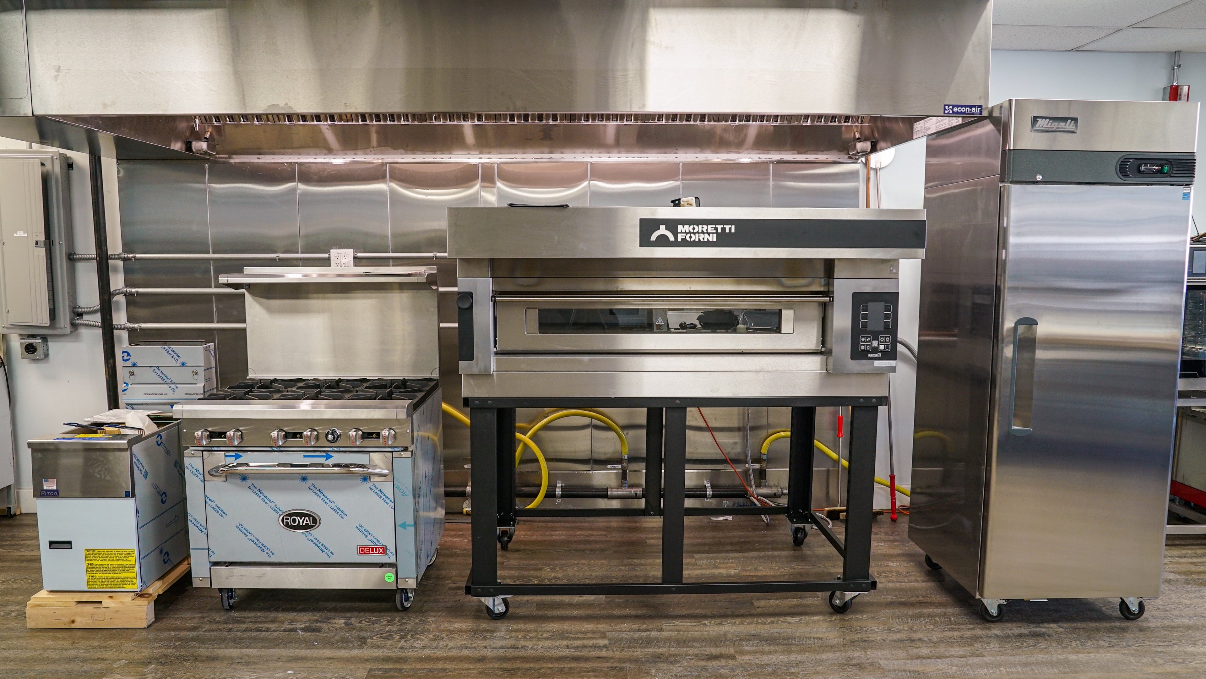 Commercial kitchen equipment including ovens and refrigerators in a showroom 
setting.
